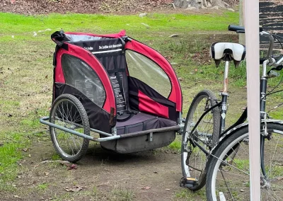 Carrito de arrastre rojo para niños junto a bicicletas de arriendo